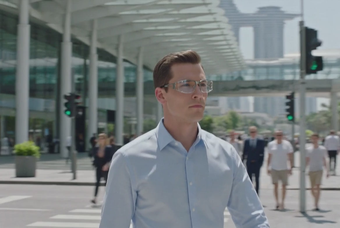 Product promotional video of silver metallic futuristic eyeglasses with clear lenses, featuring lifestyle scenes of man and woman wearing the glasses