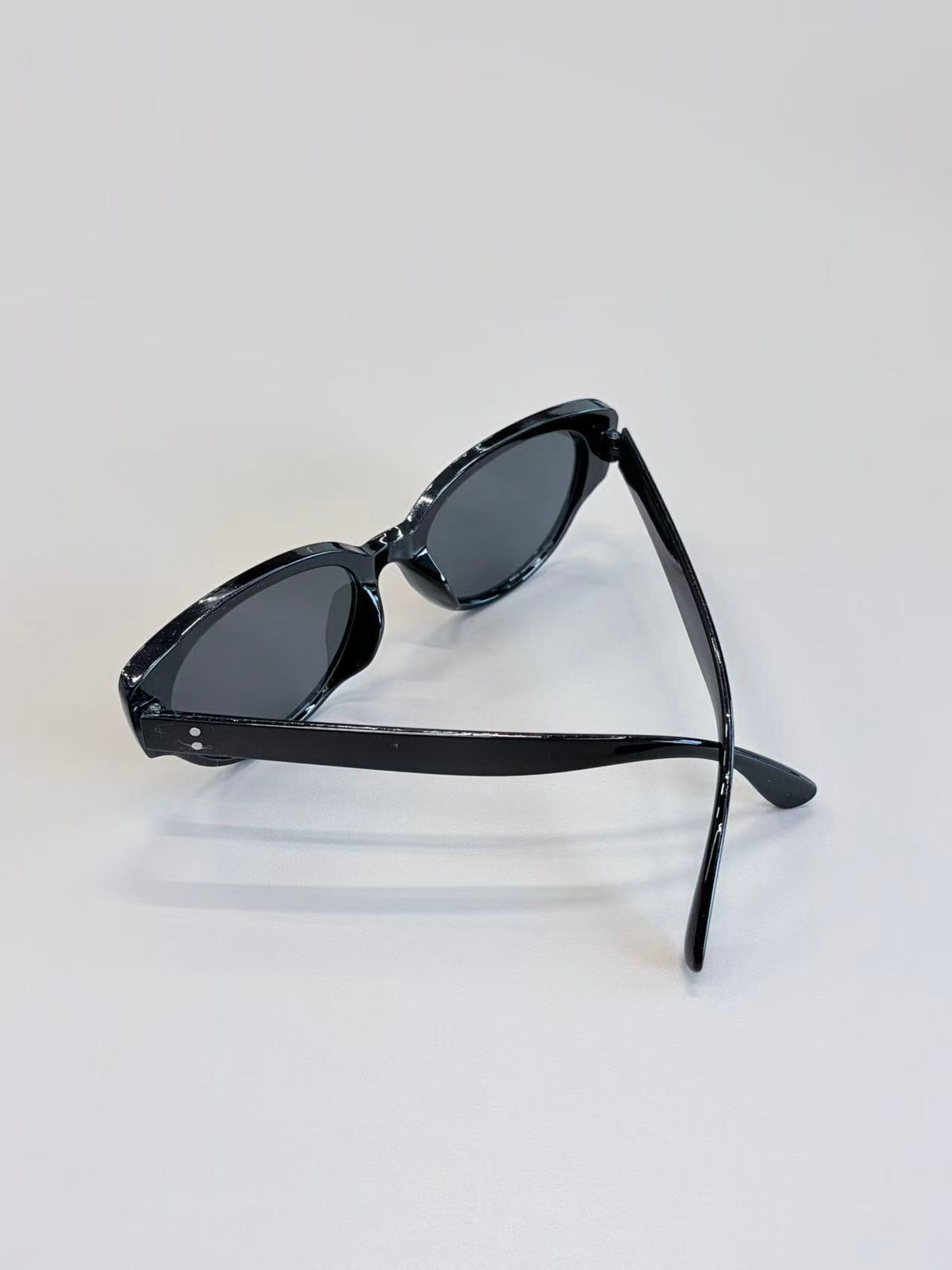 Black cat-eye sunglasses with dark lenses, displayed on a clean white surface.